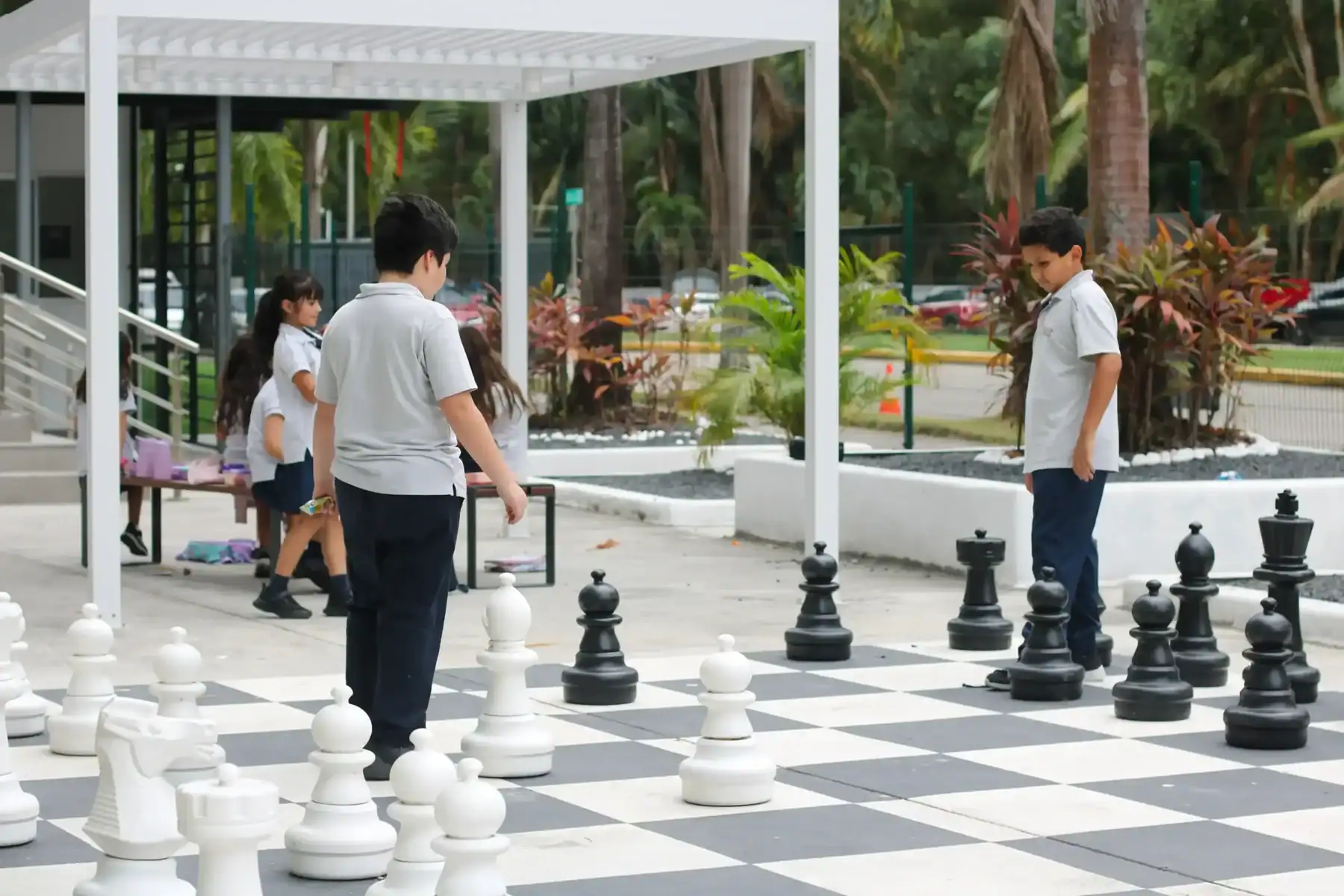 Students playing chess outdoors at Boston School International campus.