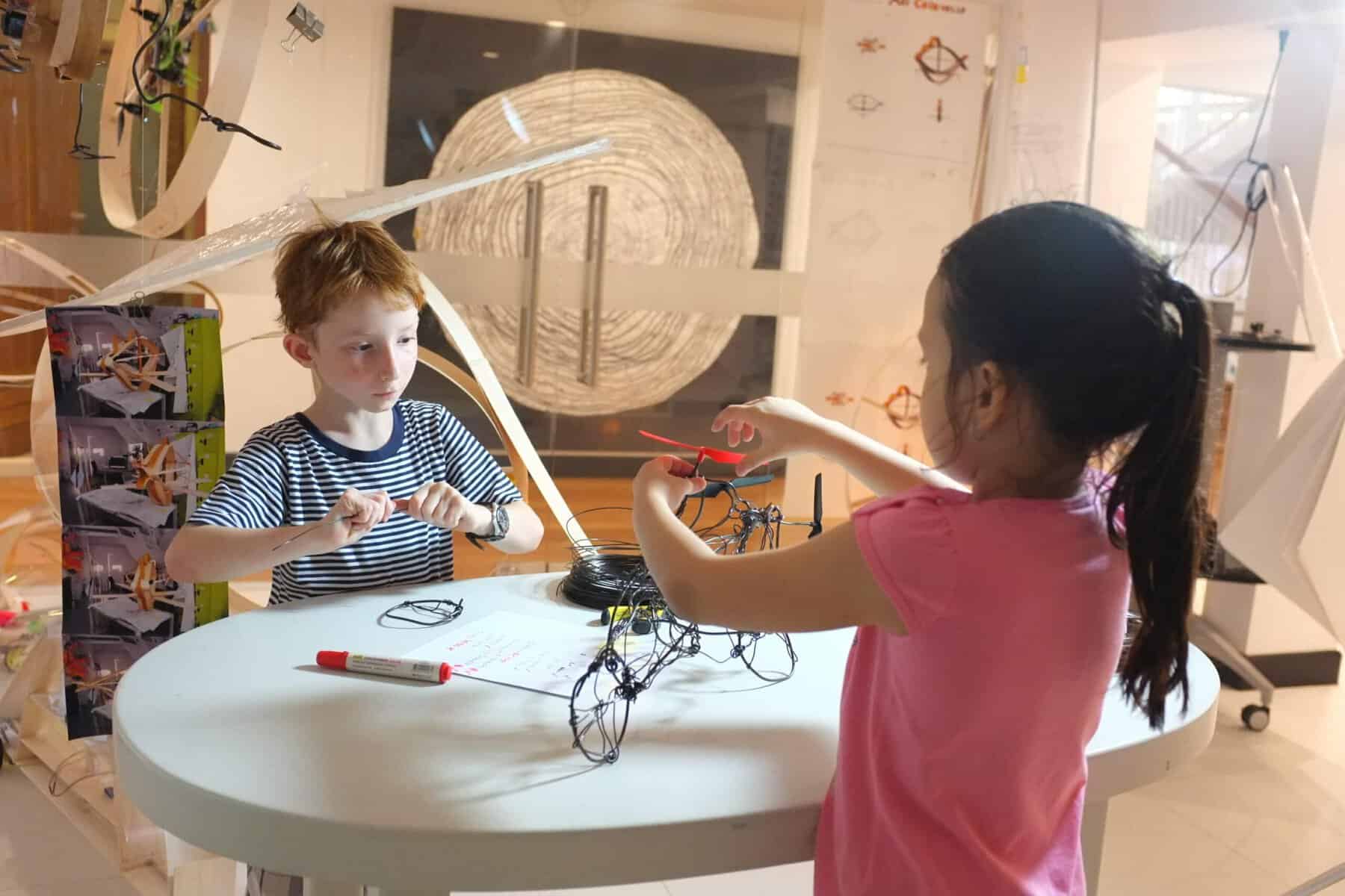 Children engaging in STEM activities with robotics and electronics in a modern educational space.