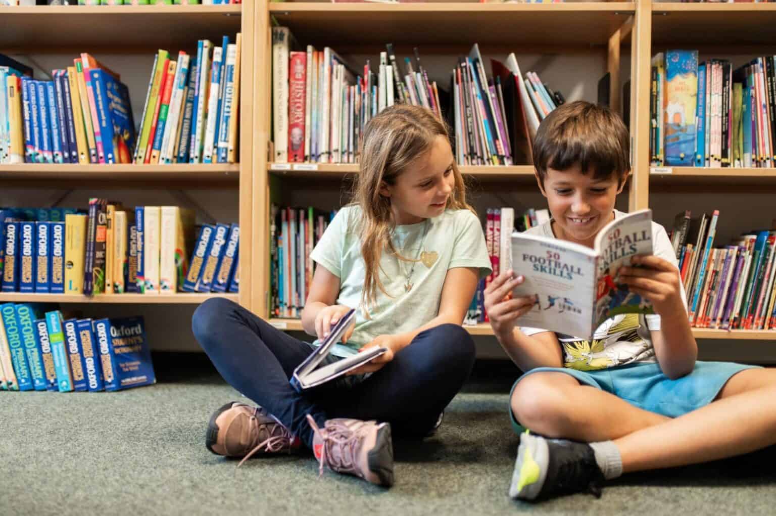 Young children reading books in a school library for a wholesome educational setting.