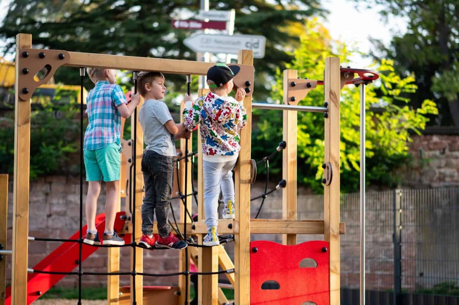 Kids playing on outdoor wooden playground jungle gym at a school yard.