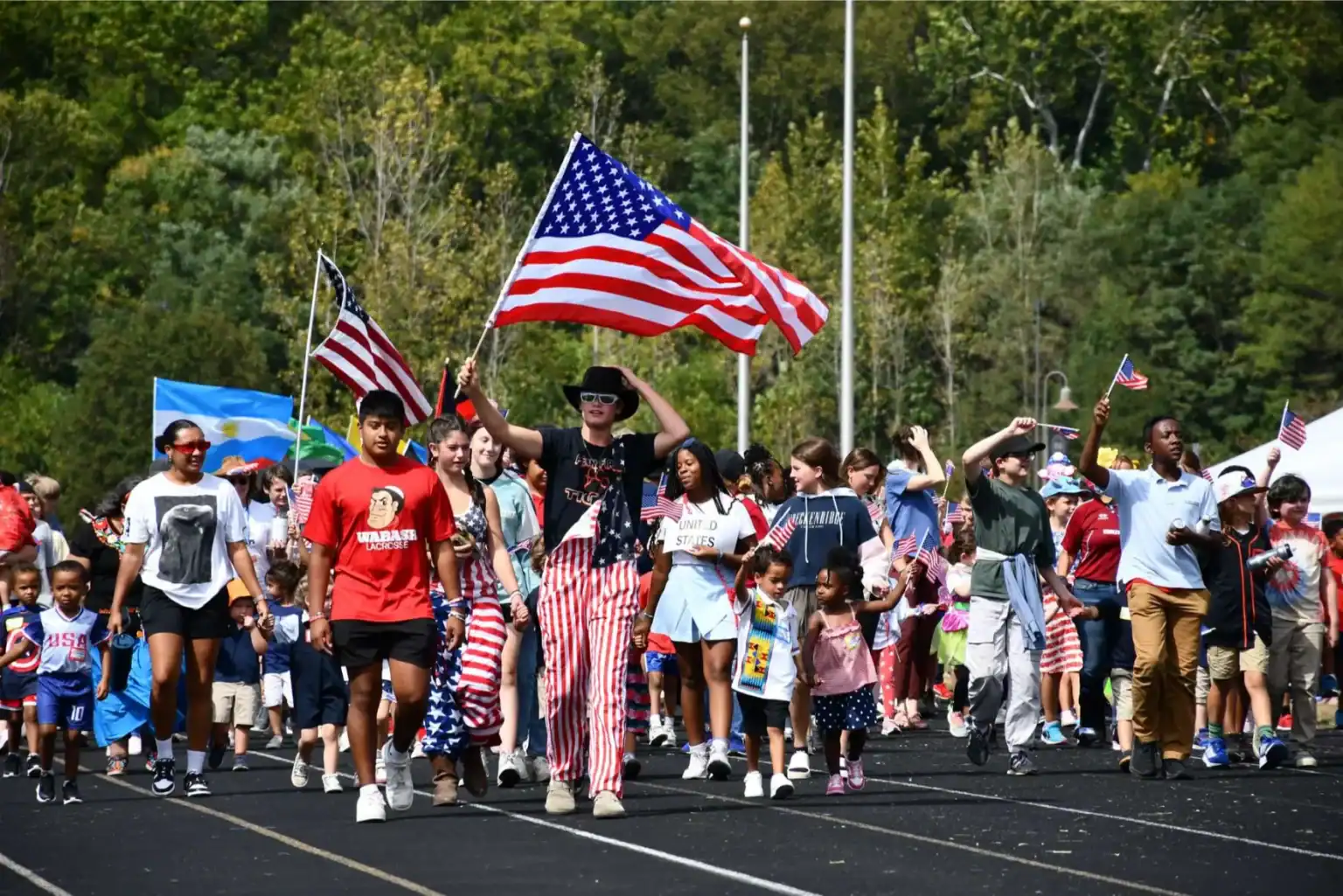 Patriotic school students waving American flags at a parade for US Independence Day celebrations.