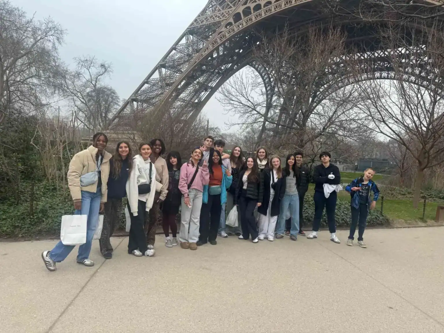 Bright diverse students posing near Eiffel Tower, showcasing world-class education and international student community.