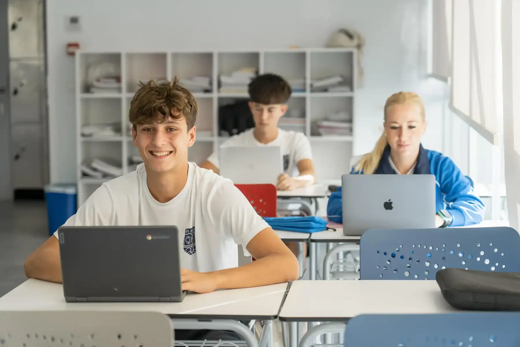 Students using laptops in a modern classroom at a world school, fostering global education.
