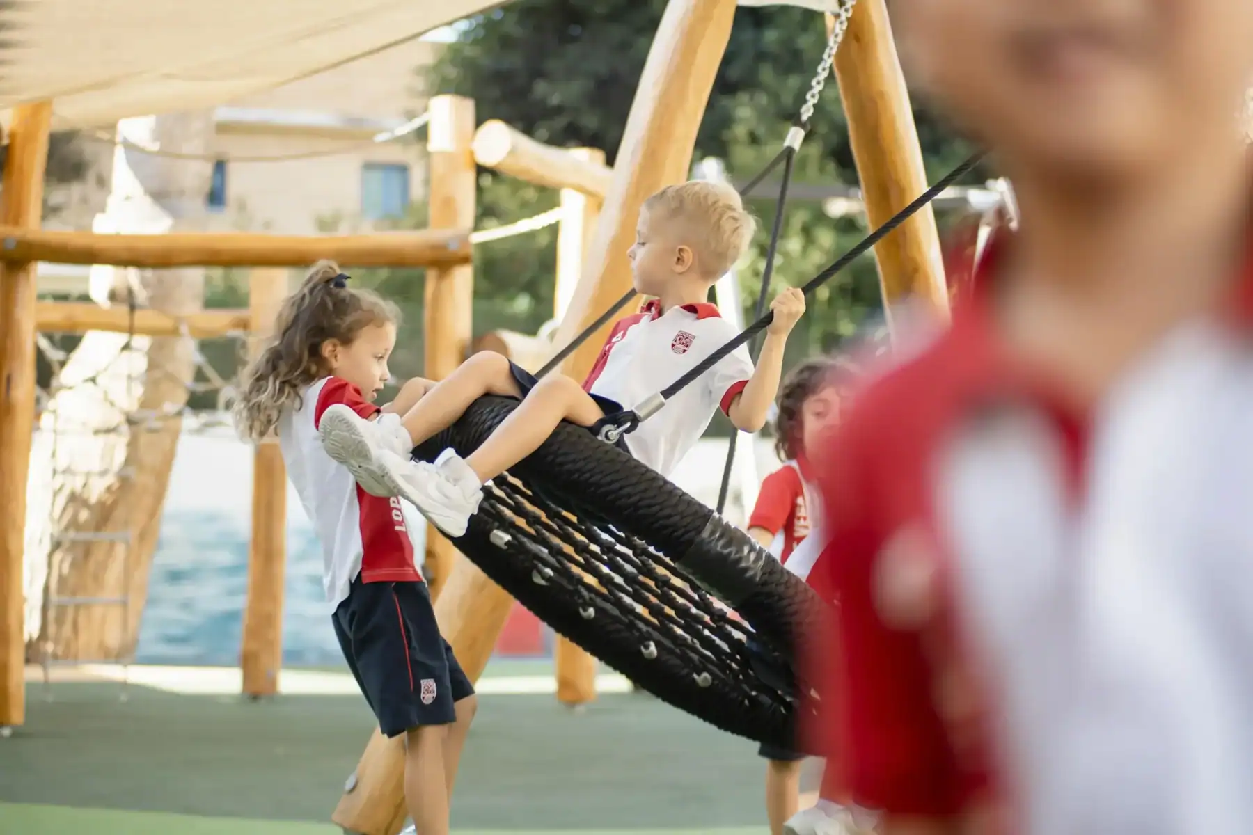 Children playing on outdoor playground swing set at World Schools.