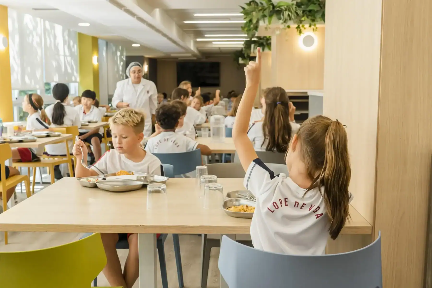 Kids raising hands in school cafeteria, diverse students enjoying nutritious meal at World Schools.