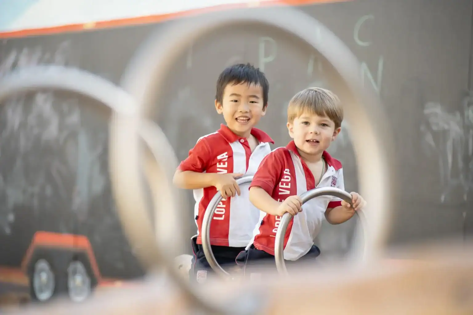 Happy young children playing on playground equipment at a World Schools event, promoting education and student development.