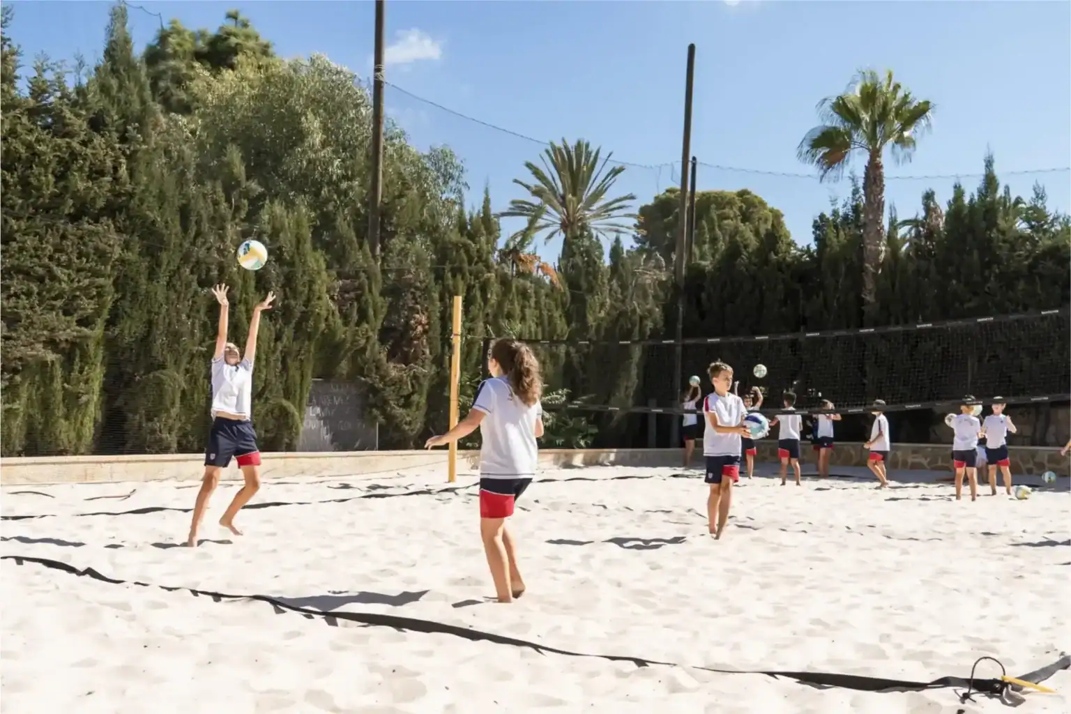 Kids playing beach volleyball outdoors at a global school.