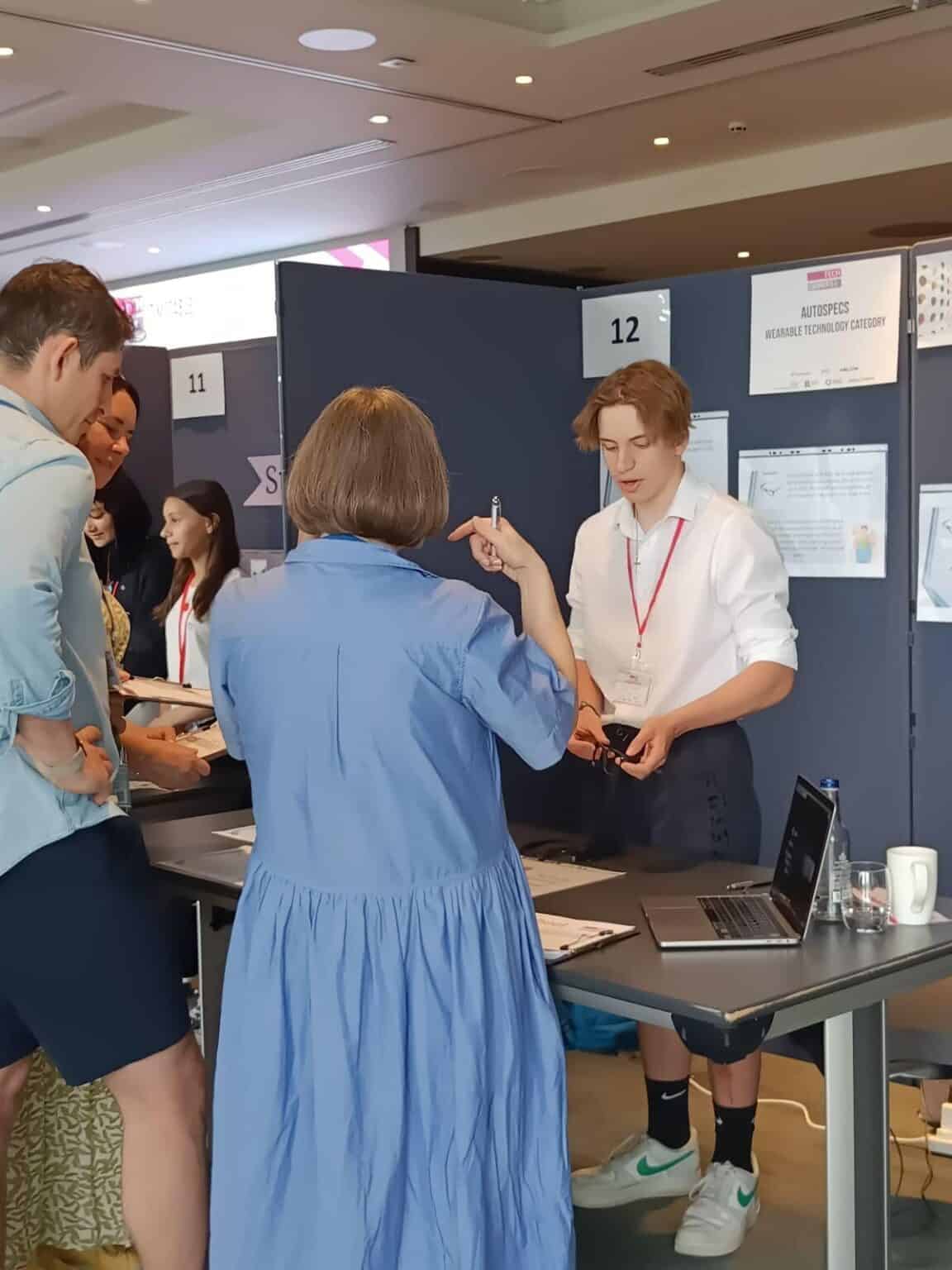 Innovative students presenting at a world schools event showcasing advanced wearable technology projects.