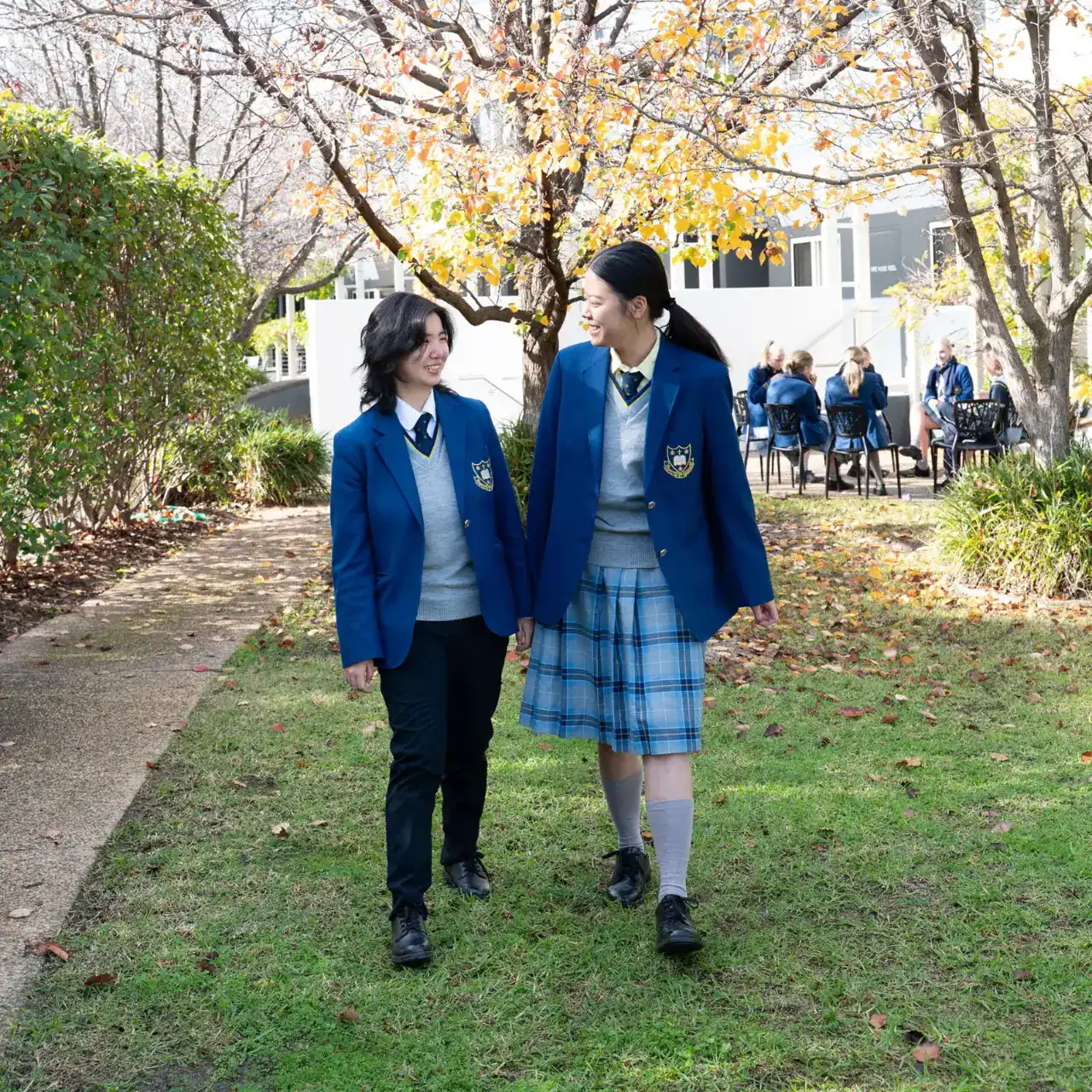 Happy students walking on school grounds with autumn scenery at an international school.