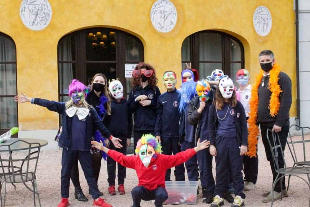 Colorful students wearing masks celebrate during a school event at World Schools.