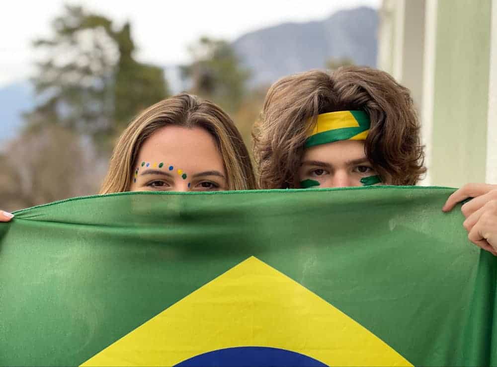 Bright smiling students holding Brazilian flag, celebrating cultural diversity at World Schools.