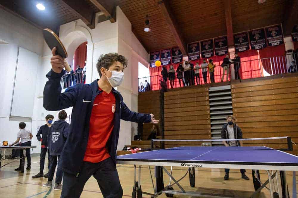 Active student playing table tennis at a school sports event.
