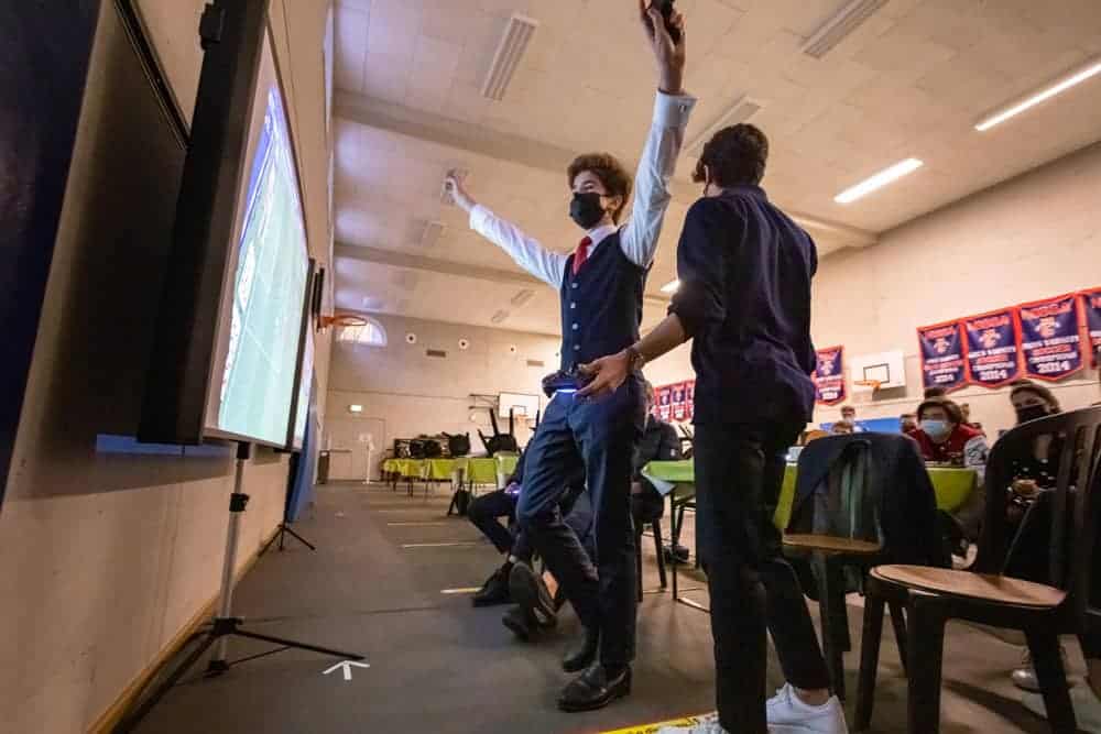 Energetic students celebrating in a school gym for an academic event or sports achievement.