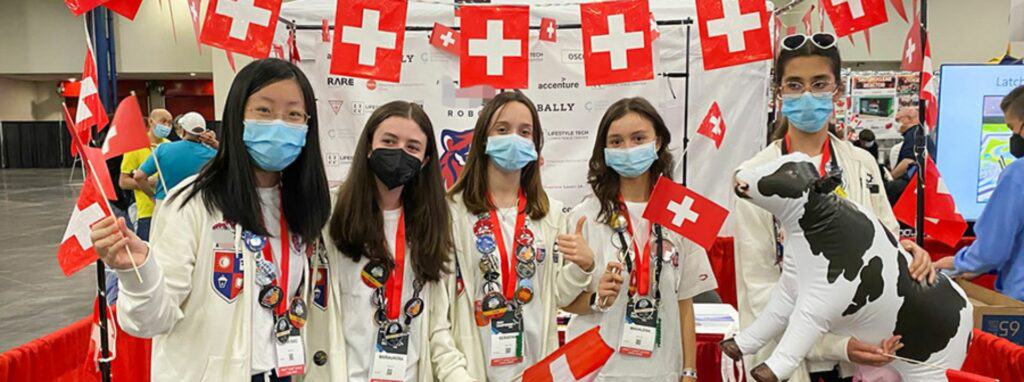 Bright Swiss School students celebrating at an international event with flags, promoting global education and intercultural exchange.