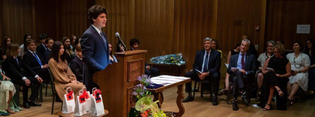 Dedicated student delivering speech at school assembly in front of attentive audience.