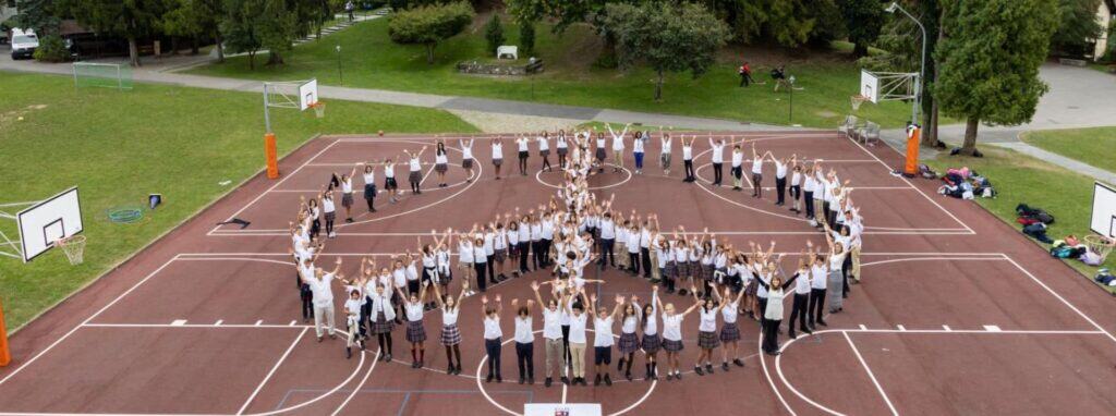 Students forming the word "LOVE" on an outdoor basketball court at a World Schools campus.