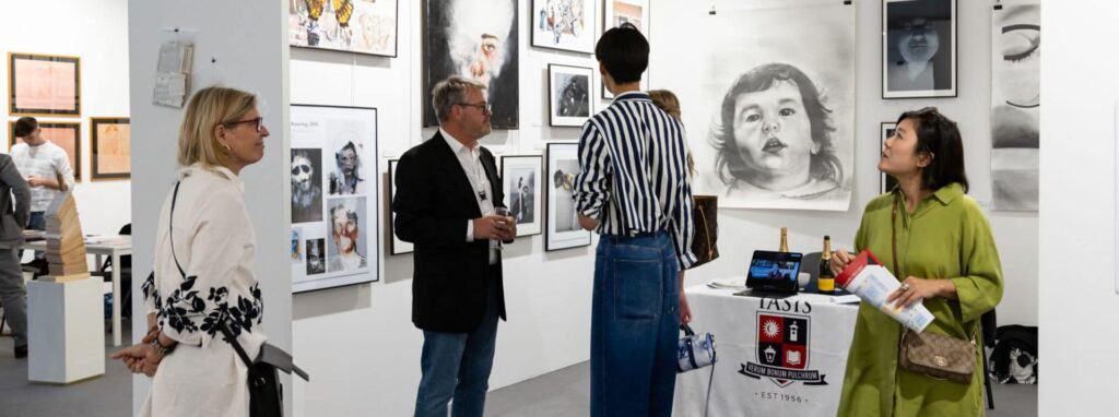 Art gallery with visitors observing portraits at a World Schools event, showcasing artistic talent and international student achievements.