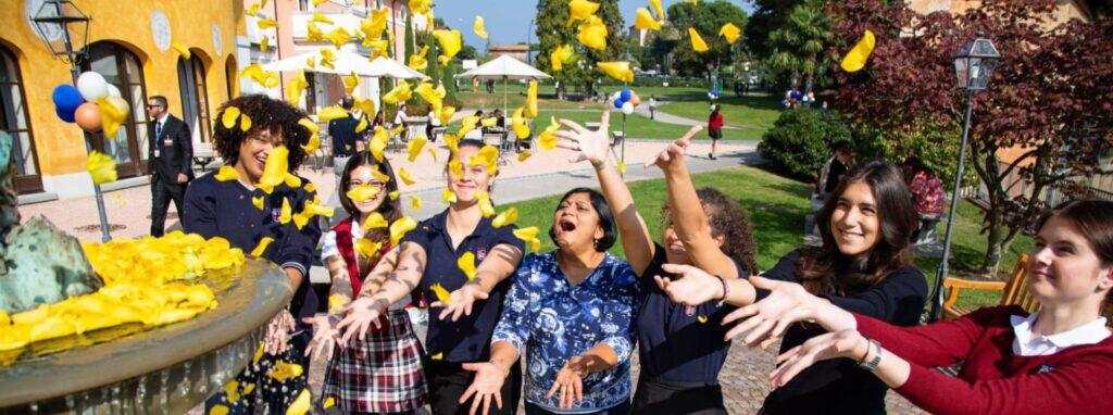 Colorful school celebration with children throwing yellow confetti outdoors, showcasing vibrant learning environment.