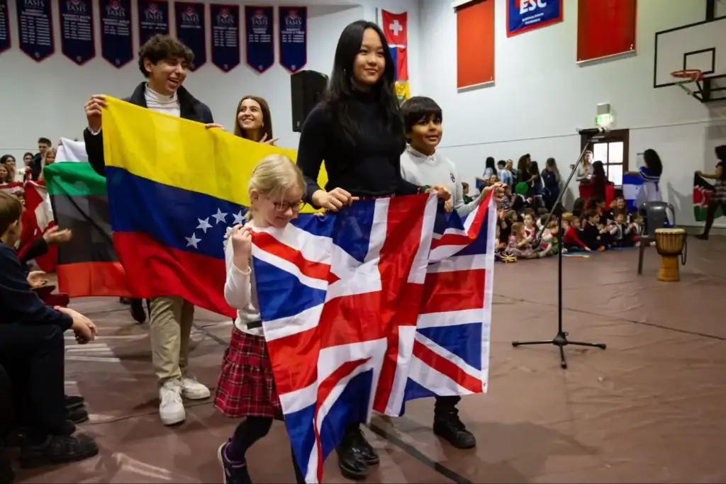 International students celebrating with flags at an indoor school event.