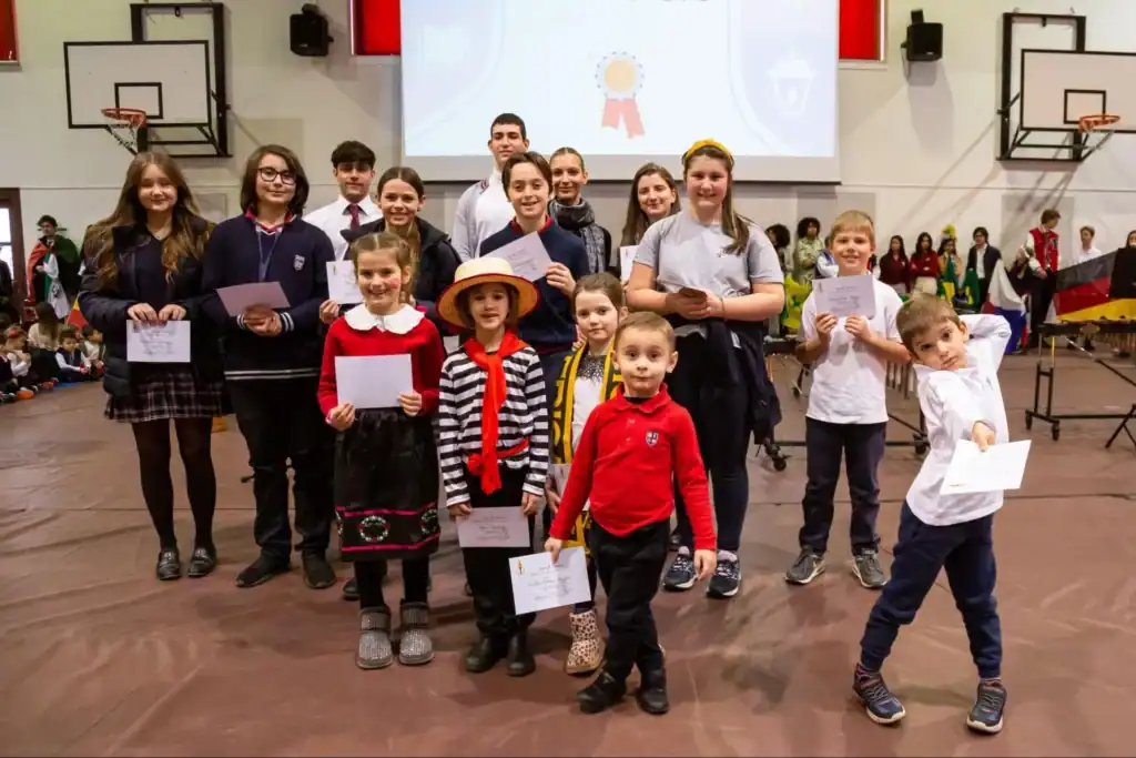 Students holding awards at a World Schools event in an indoor gymnasium.