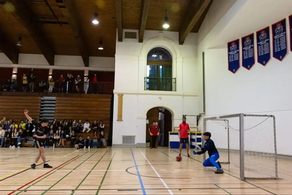 Bright indoor sports facility at World Schools with students playing soccer and volleyball.
