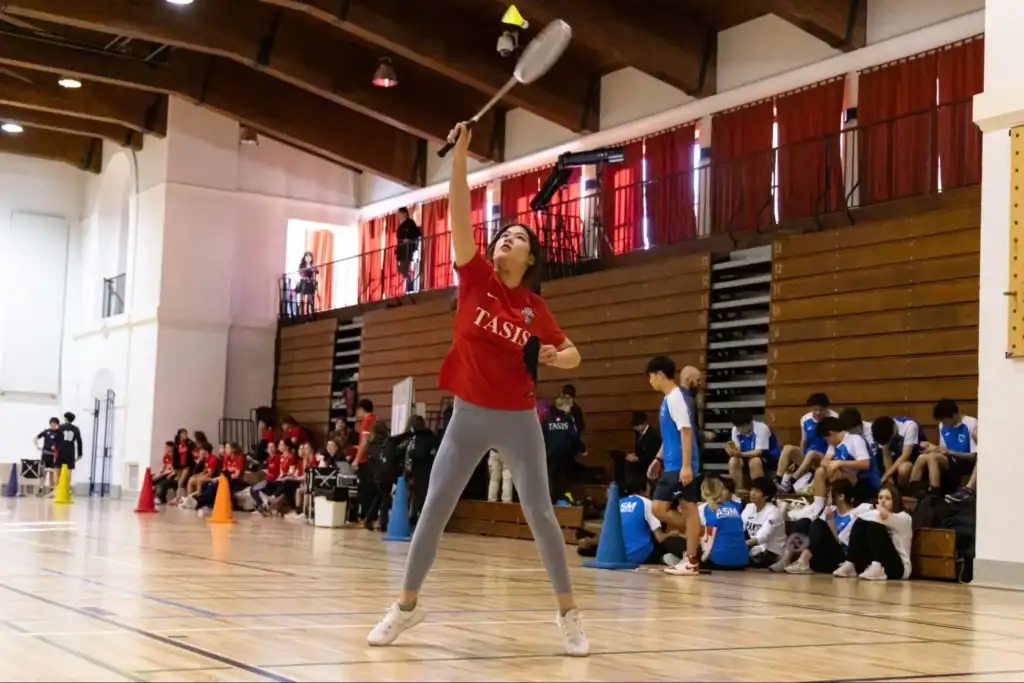Young female badminton player practicing in indoor gymnasium at World Schools event.