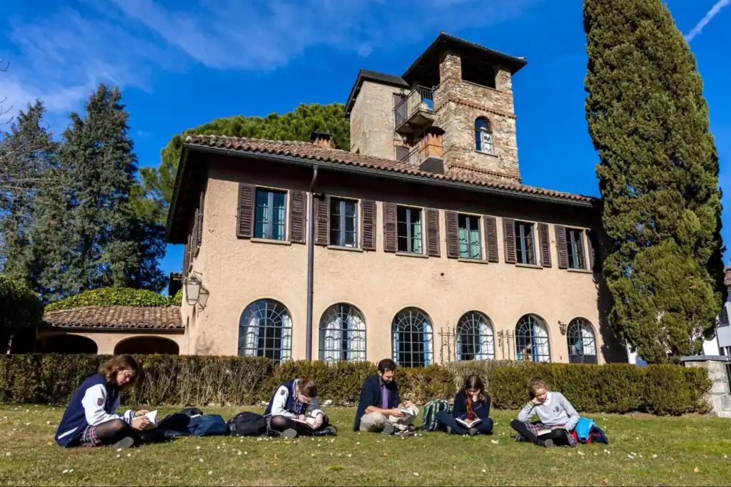 Students studying outdoors at a historic school building; international, private, or boarding school environment.