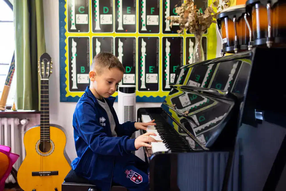 This Month at TASIS: March 2025 12 Creative young student playing piano in classroom with musical instruments and vibrant educational decor.
