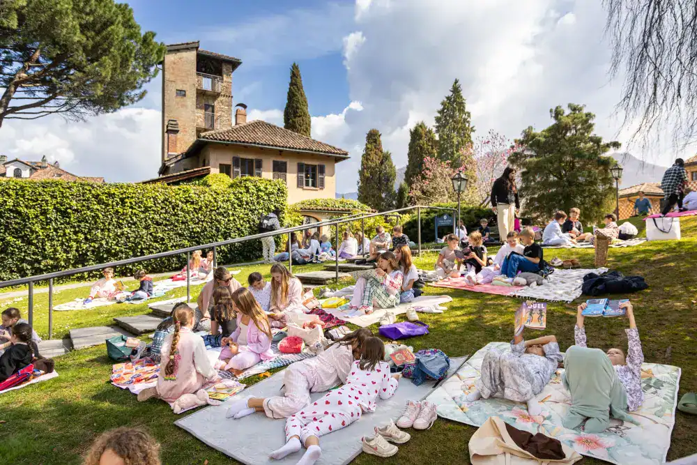 This Month at TASIS: March 2025 23 Children studying outdoors at a school picnic in a picturesque garden setting.