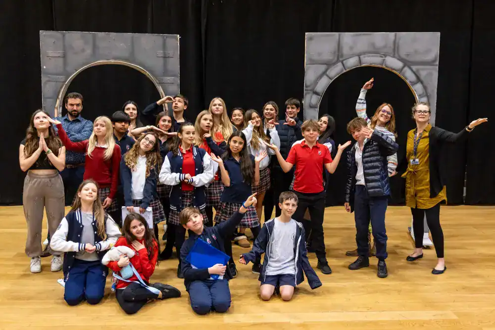 This Month at TASIS: March 2025 25 Brightly dressed students and teachers participating in a school play or performance at an international school.