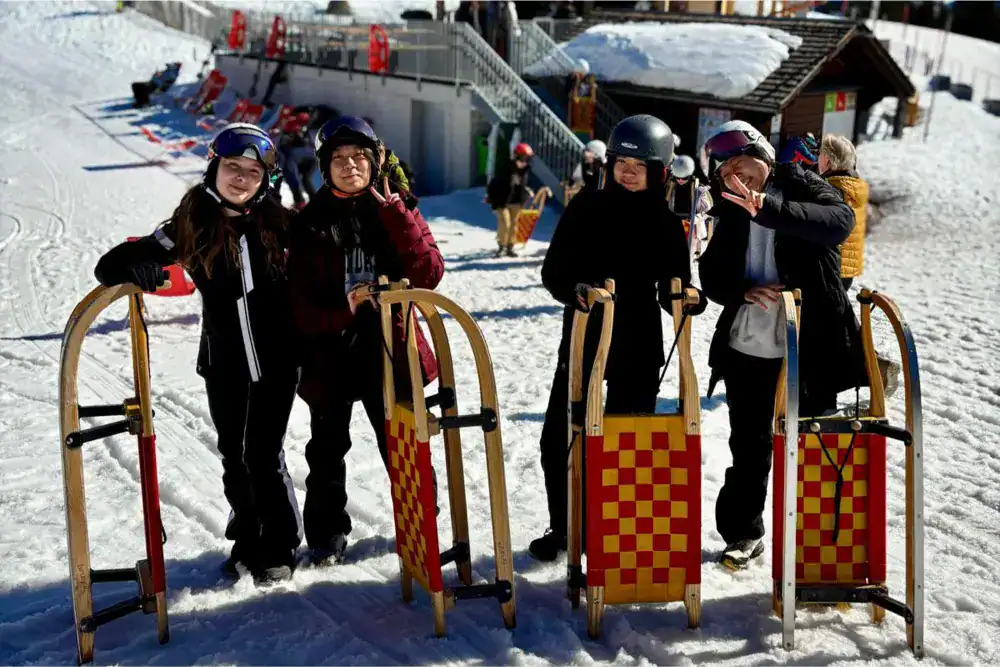 This Month at TASIS: March 2025 5 Sledding group at snowy ski resort with children wearing helmets and winter jackets.