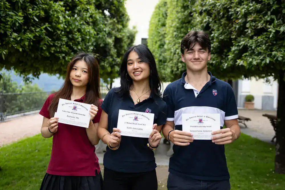 This Year at TASIS: 2024 24 Diverse students holding certificates outside, showcasing academic achievement at World Schools.