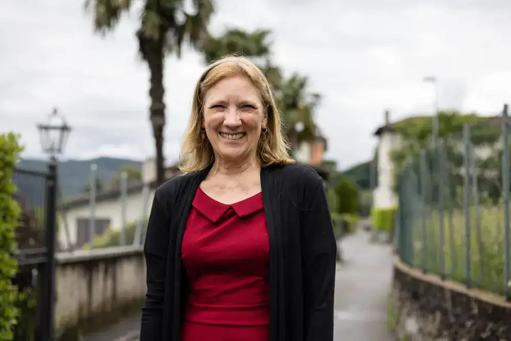 This Year at TASIS: 2024 27 Widow smiling outdoors at a school with trees and pathways in the background.