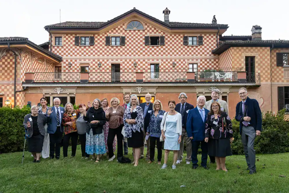This Year at TASIS: 2024 37 Elegant group of adults outdoors in front of a picturesque Italian-style villa, celebrating education excellence at World Schools event.