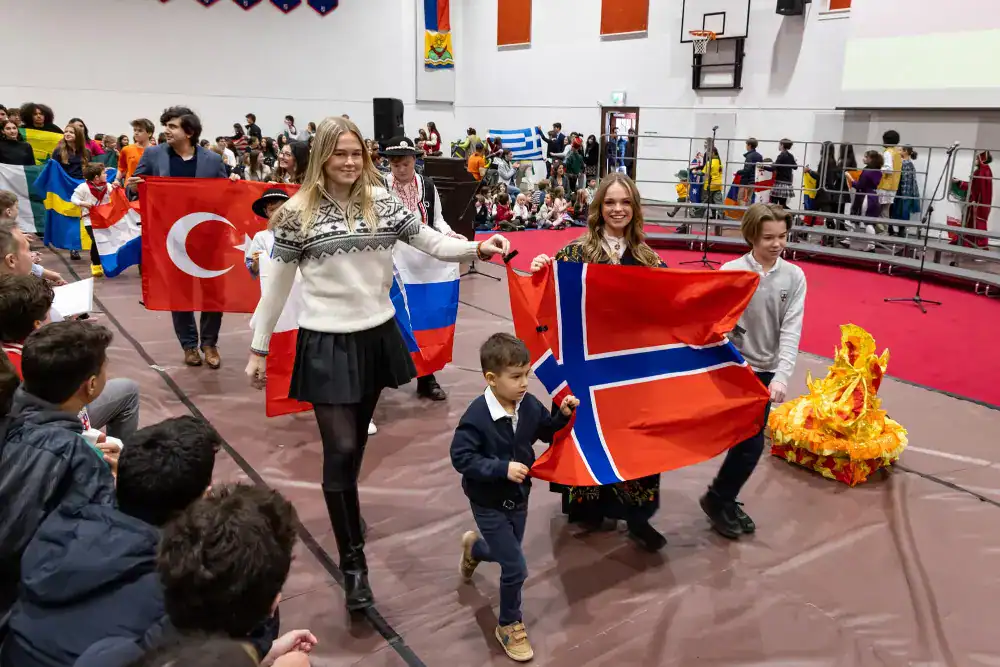 This Year at TASIS: 2024 3 Bright students holding international flags during a cultural event at World Schools, promoting global education and diversity.