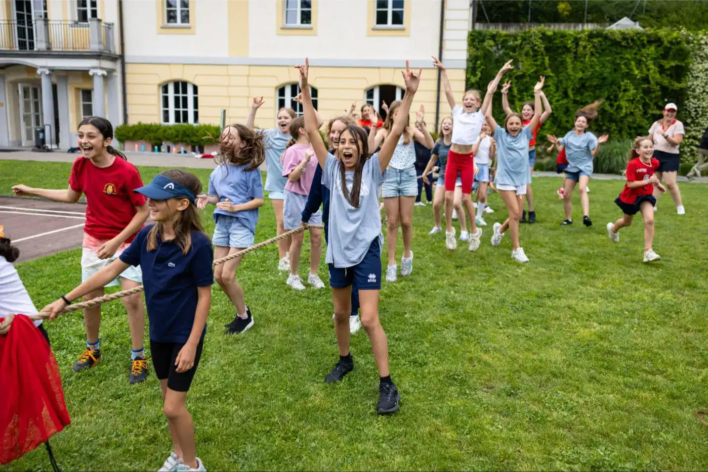 This Month at TASIS: June 2025 5 Children playing tug-of-war on school grounds, joyful outdoor activity, school children having fun, engaging in physical education, outdoor learning.