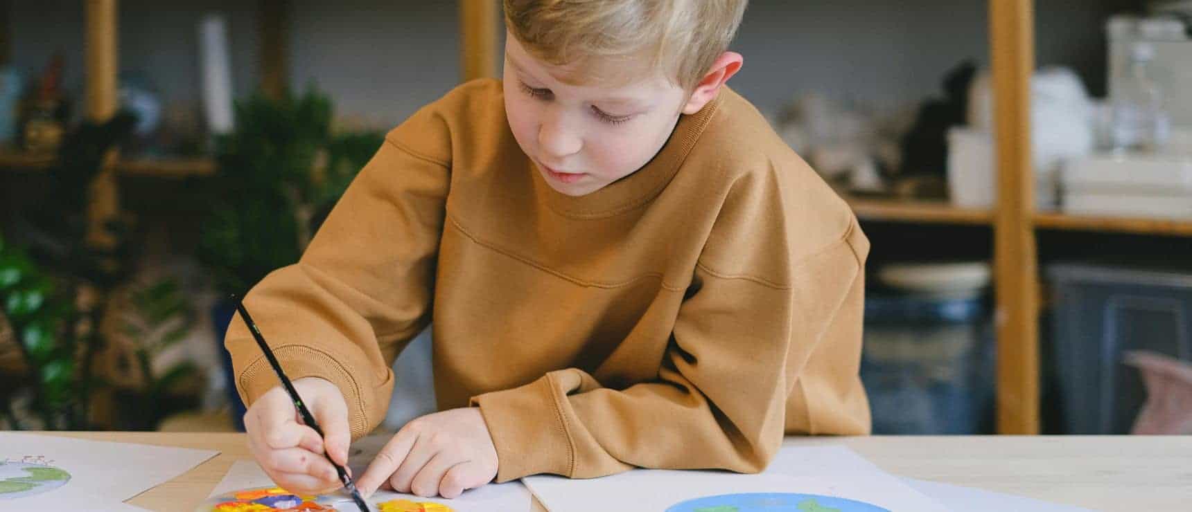 Bright young student painting colorful artwork at school for global education and innovative learning.