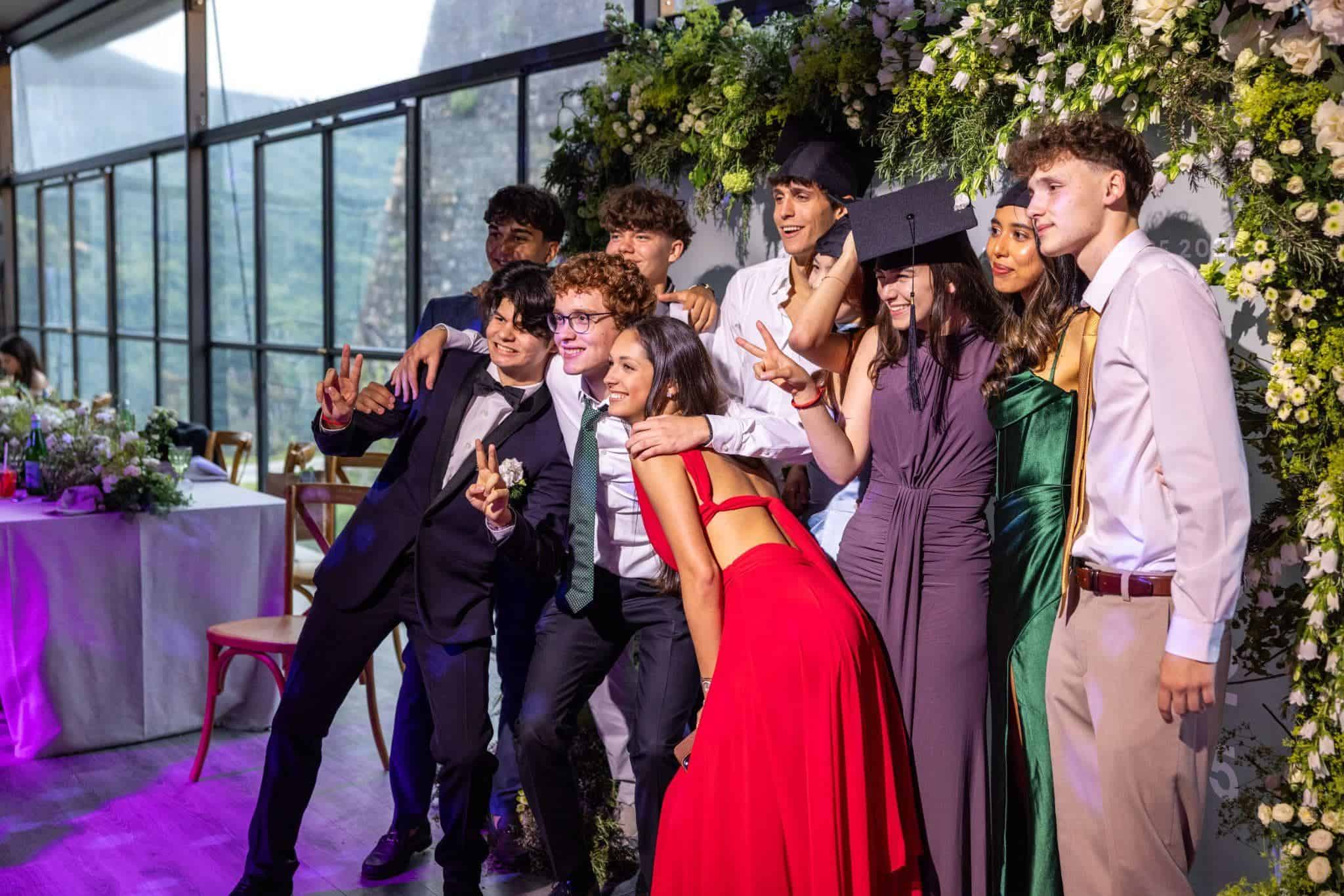 This Month at TASIS: May 2025 21 Brightly dressed graduates celebrating at a school graduation ceremony in a modern glass venue.