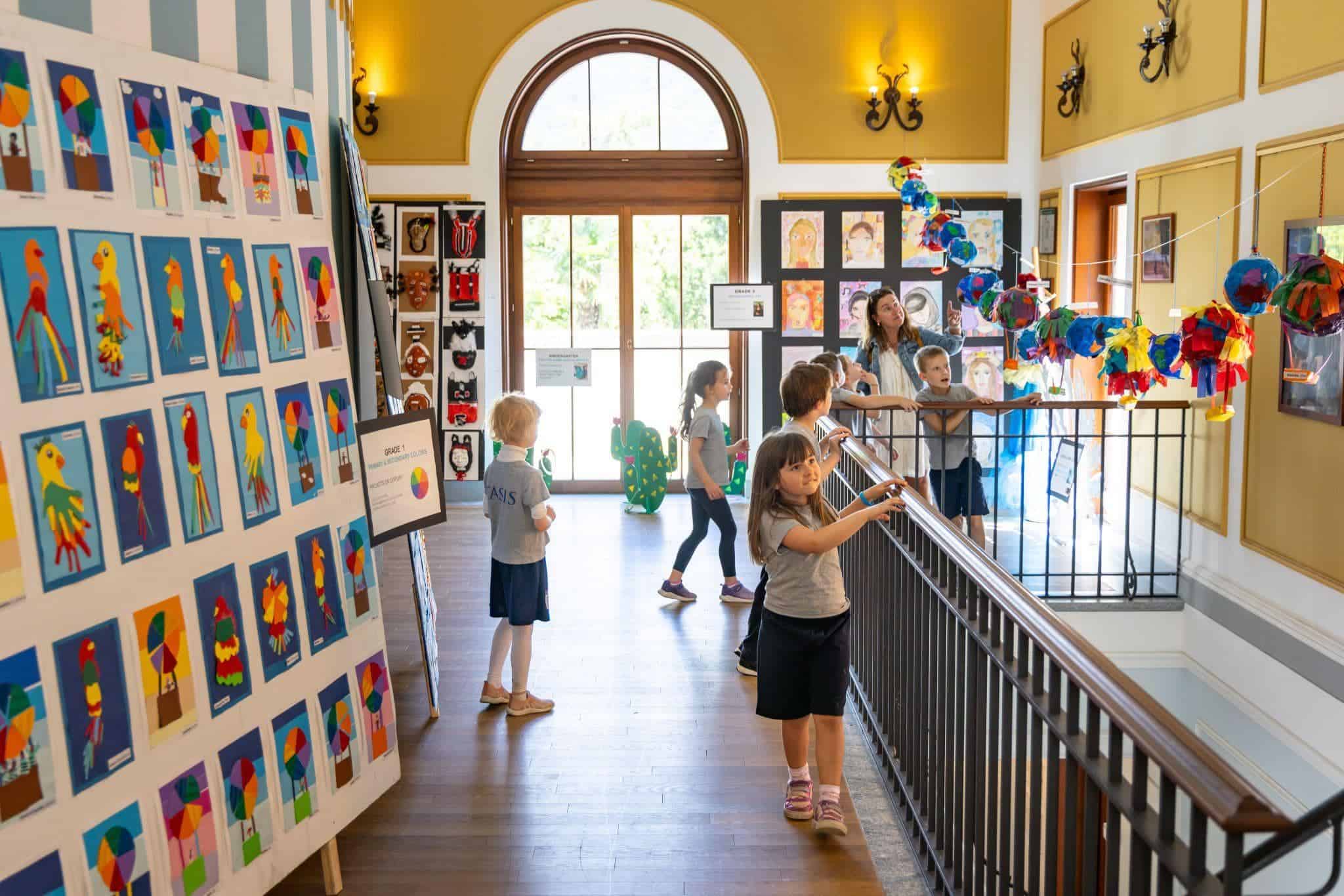 This Month at TASIS: May 2025 14 Colorful children's artwork displayed in a vibrant school art gallery.