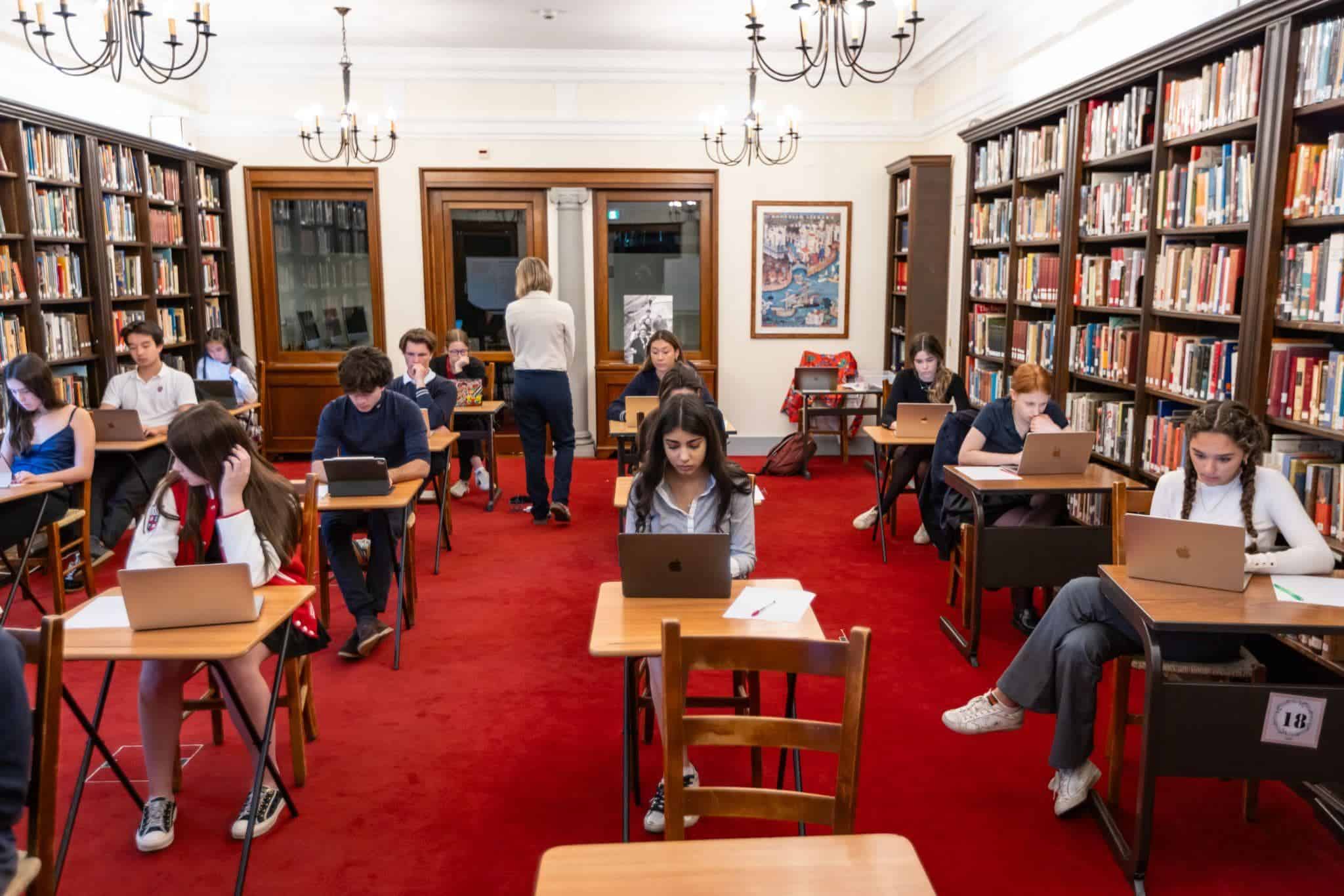 This Month at TASIS: May 2025 9 Students studying on laptops in a world schools library, promoting international education and academic excellence.