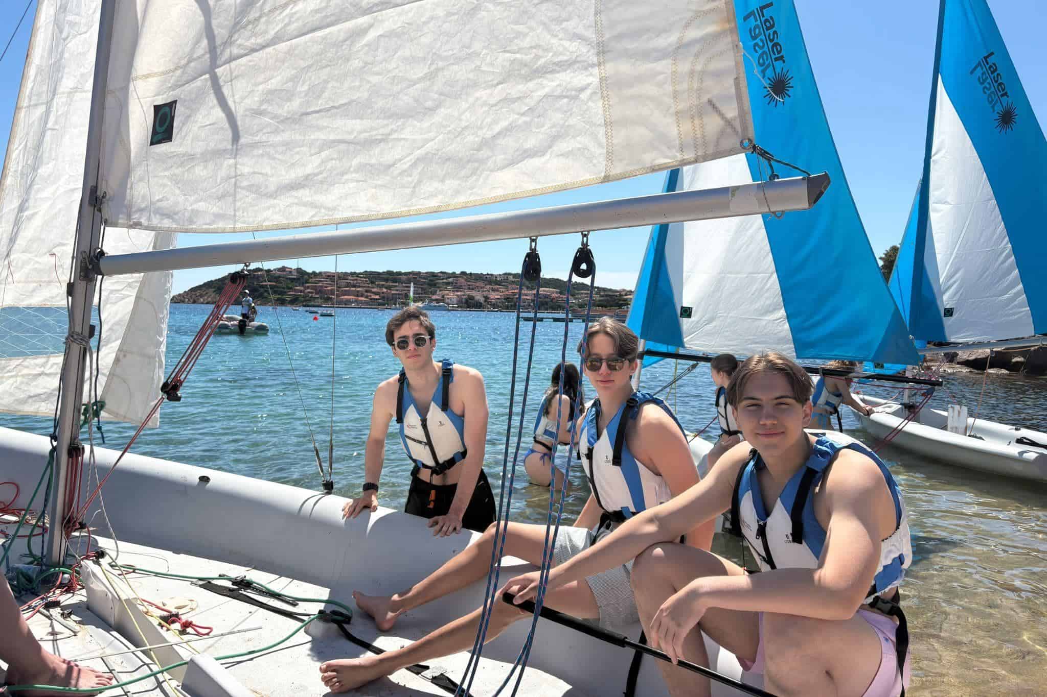 This Month at TASIS: May 2025 2 Young students sailing on a boat at a seaside school activity, promoting water sports and outdoor education.