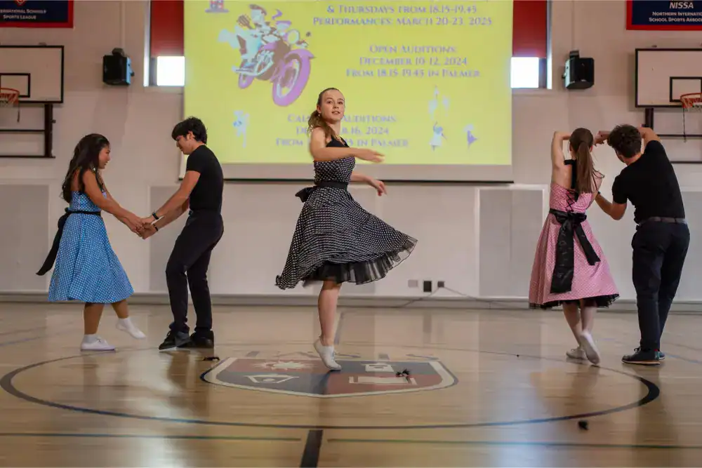 This Month at TASIS: November 2024 13 Energetic children performing traditional dance at school gym for cultural event.