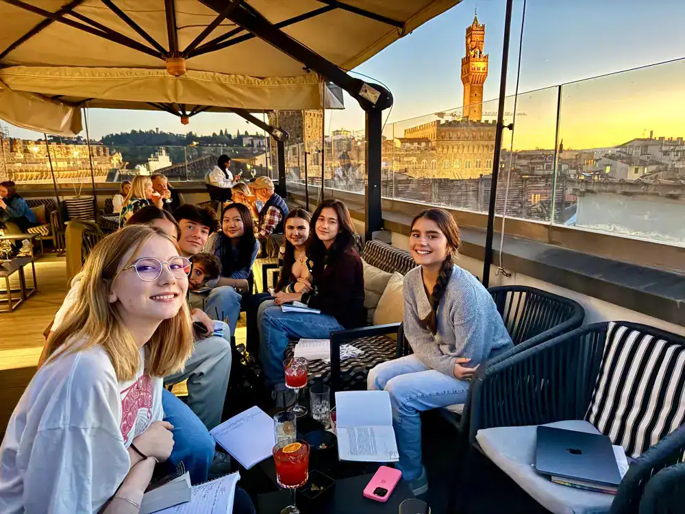 This Month at TASIS: November 2024 2 Students enjoying a rooftop classroom setting with historical Florence architecture in the background, promoting international education and global learning.