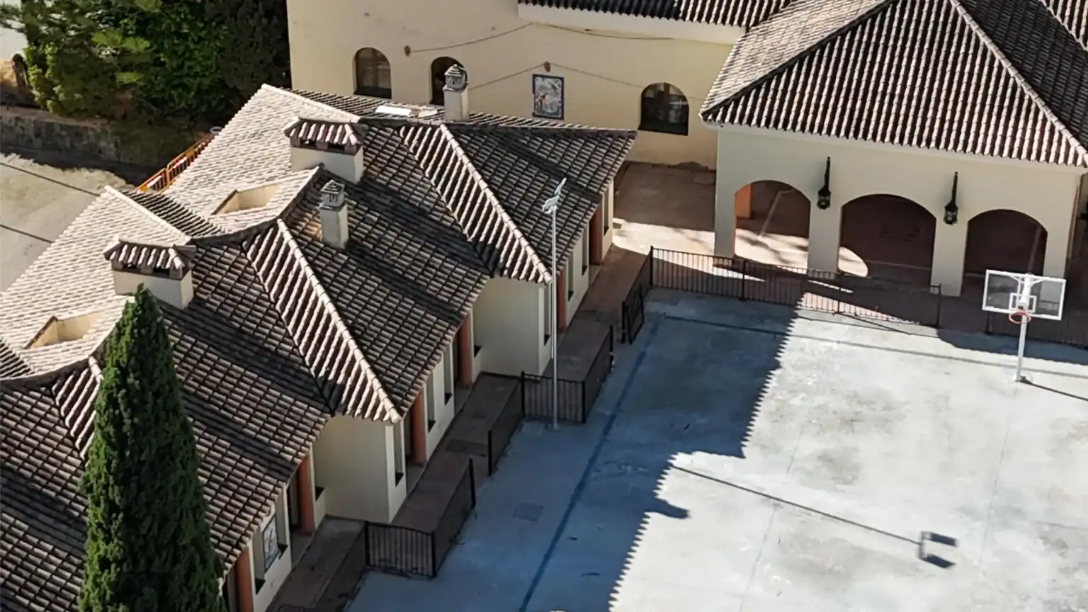 Colorful school campus with Mediterranean-style architecture, basketball court, and lush greenery for global education.