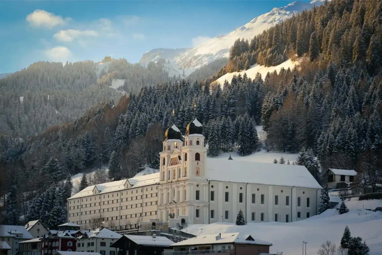 Snow-covered monastery in Alpine mountain landscape, Europe, winter, scenic view.