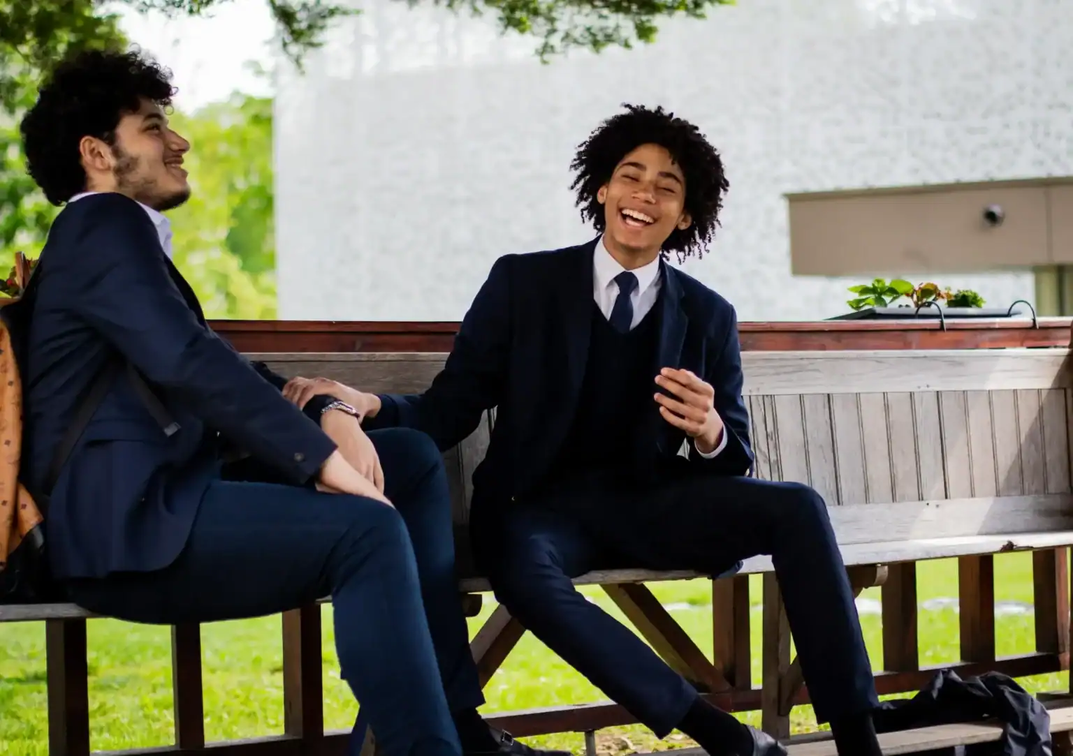Joyful students in smart uniforms sharing a laugh outdoors at a global school campus.