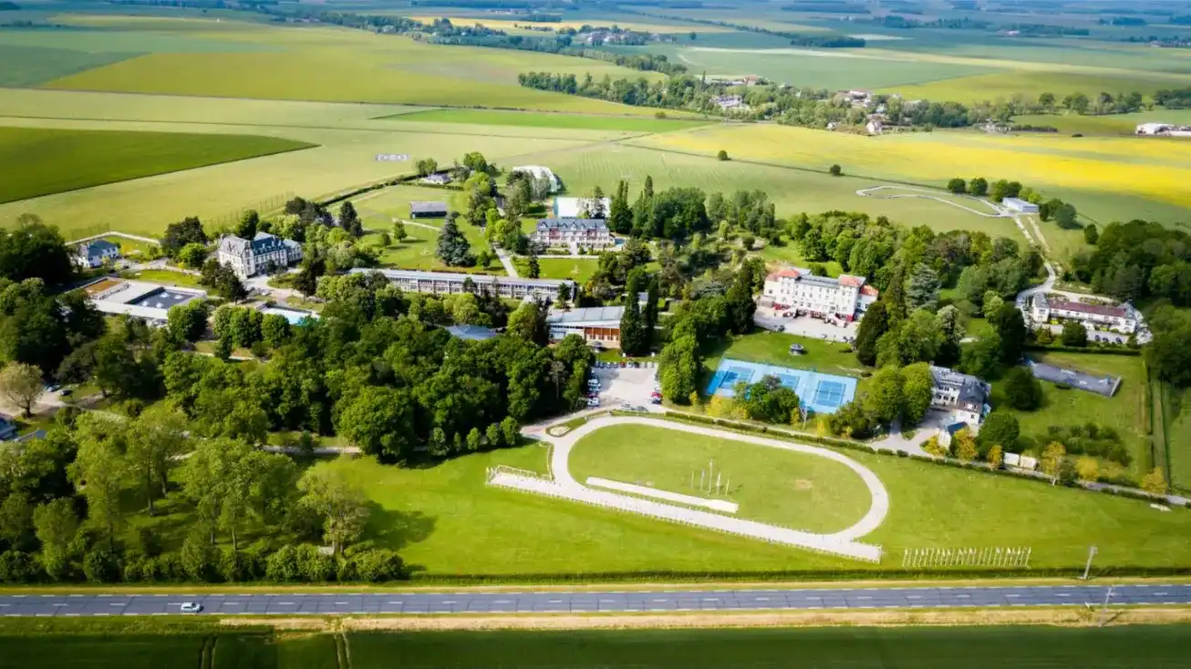 Modern international school campus surrounded by lush greenery and sports facilities.