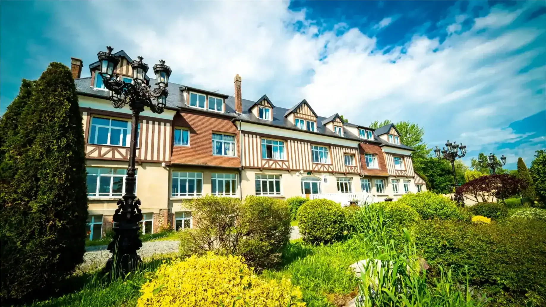 Charming European-style school building surrounded by lush greenery and decorative street lamps.