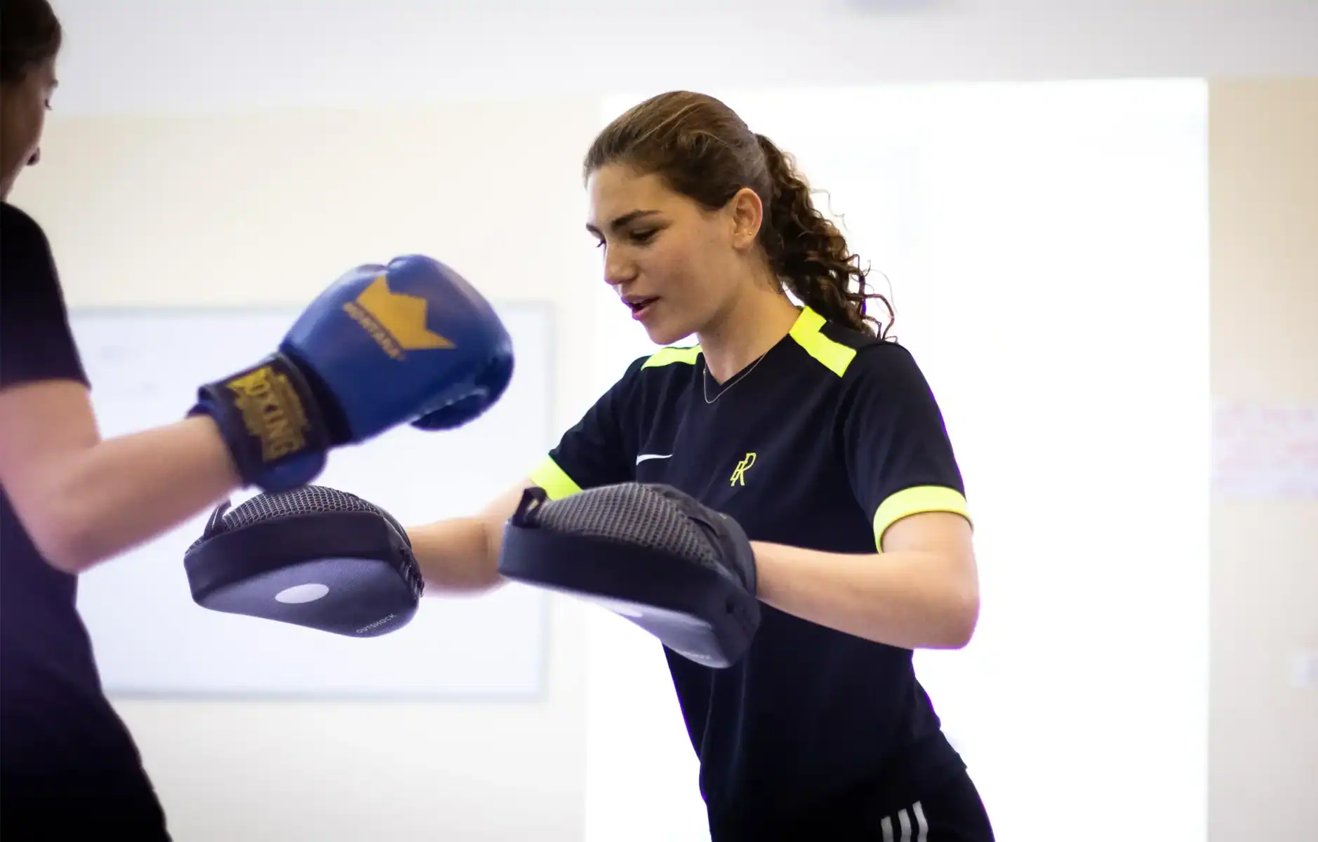 Young female student practicing boxing with coach, demonstrating sports and physical education at World Schools.