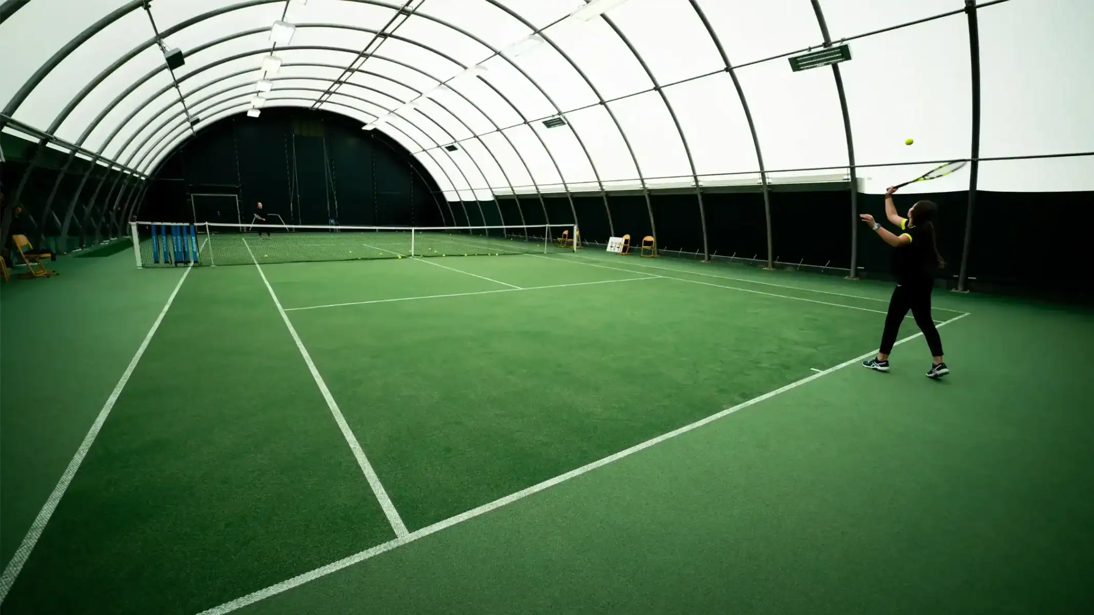 Indoor tennis training at a modern sports facility for students.